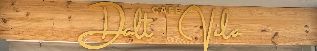 Rótulo de Dalt Vila café: letras doradas sobre una tabla de pino